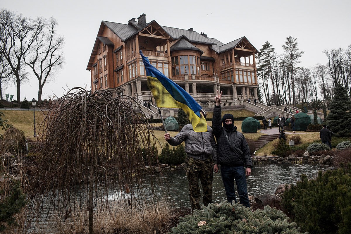 Протестующие размахивают украинским флагом в саду перед роскошным особняком, построенным бывшим президентом Януковичем, после того как он покинул Киев, 23 февраля 2014 г. в Киеве. Фото: Etienne De Malglaive / Getty Images